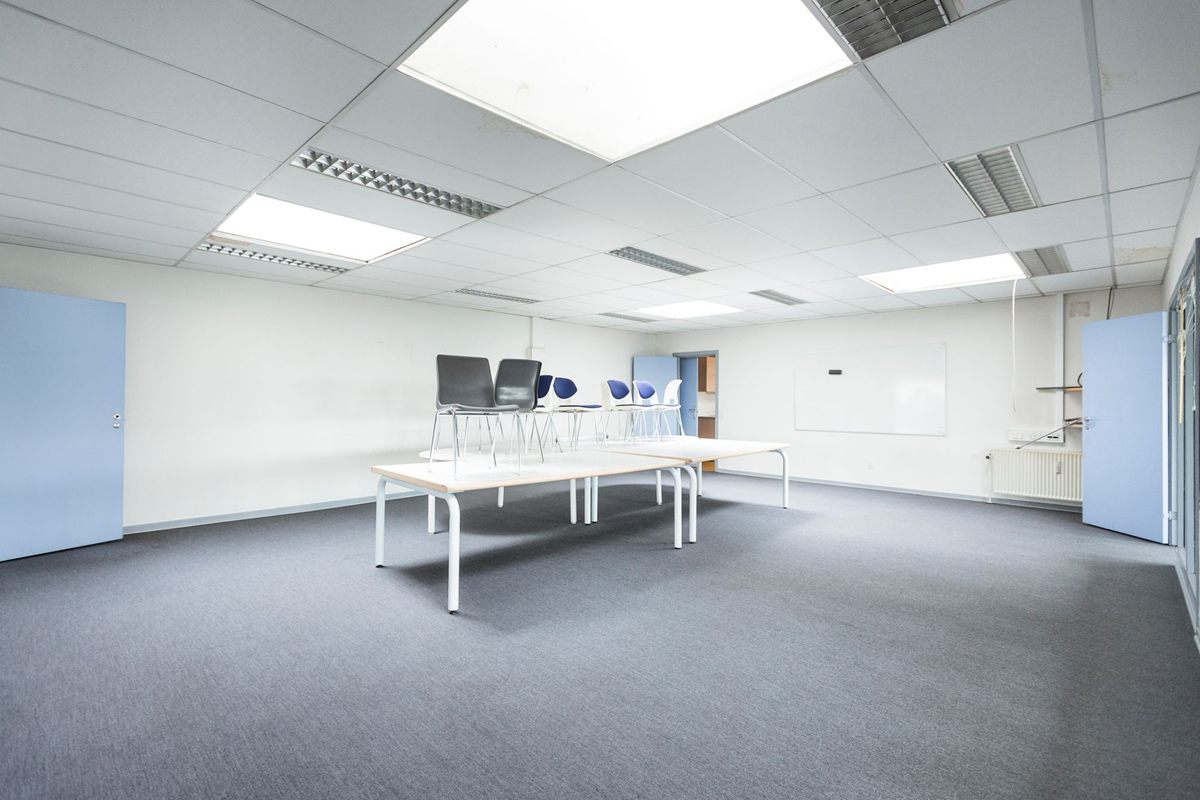 An open plan office with grey commercial carpet and white desks